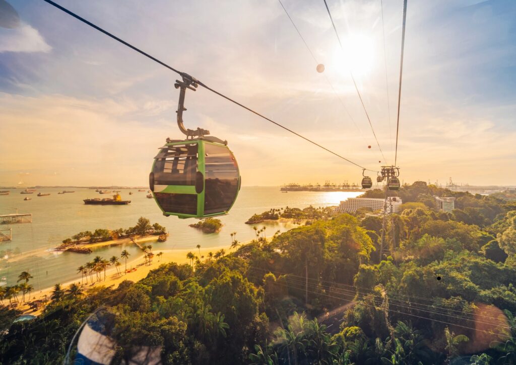 Singapore cable car gliding through the sky at sunset, with vibrant orange and purple hues illuminating the scene.
