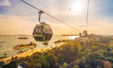 Singapore cable car gliding through the sky at sunset, with vibrant orange and purple hues illuminating the scene.