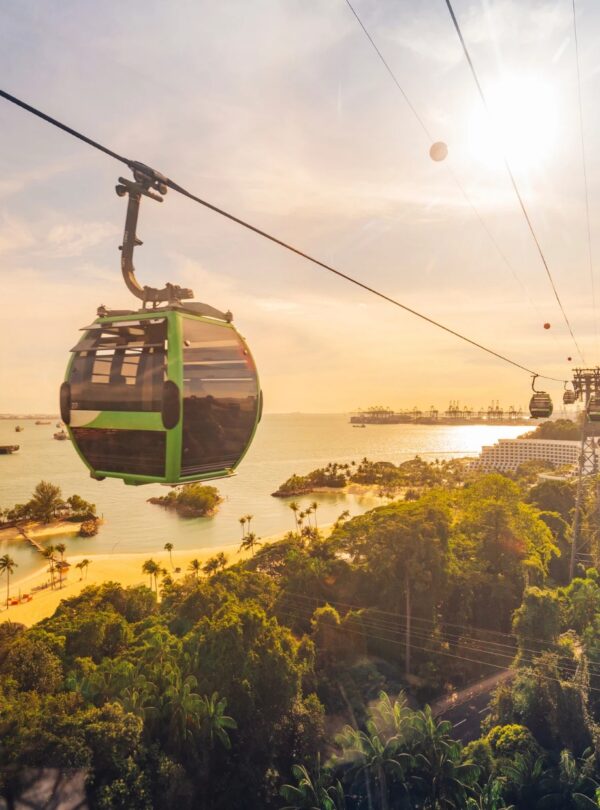 Singapore cable car gliding through the sky at sunset, with vibrant orange and purple hues illuminating the scene.