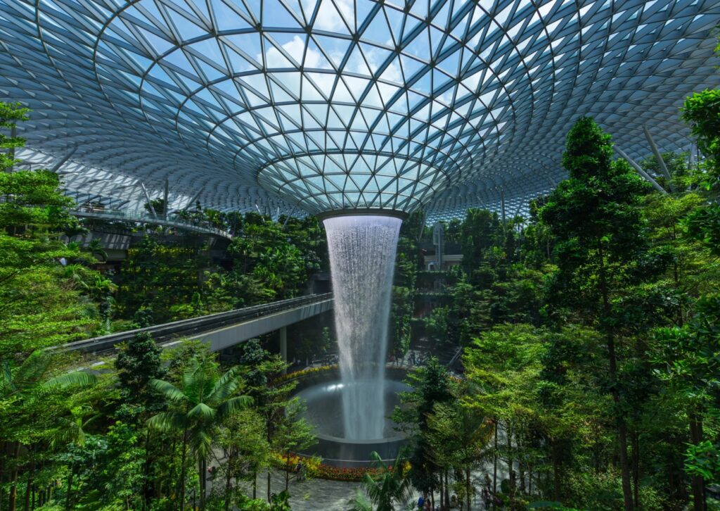 Jewel Changi Airport features a beautiful waterfall nestled in a tropical forest, enhancing the natural beauty of the space.