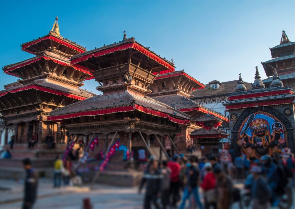 A panoramic view of Kathmandu, Nepal, showcasing its vibrant cityscape and surrounding mountains under a clear blue sky.