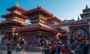 A panoramic view of Kathmandu, Nepal, showcasing its vibrant cityscape and surrounding mountains under a clear blue sky.