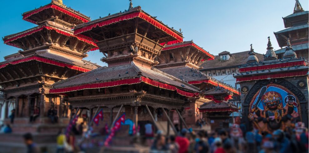 A panoramic view of Kathmandu, Nepal, showcasing its vibrant cityscape and surrounding mountains under a clear blue sky.