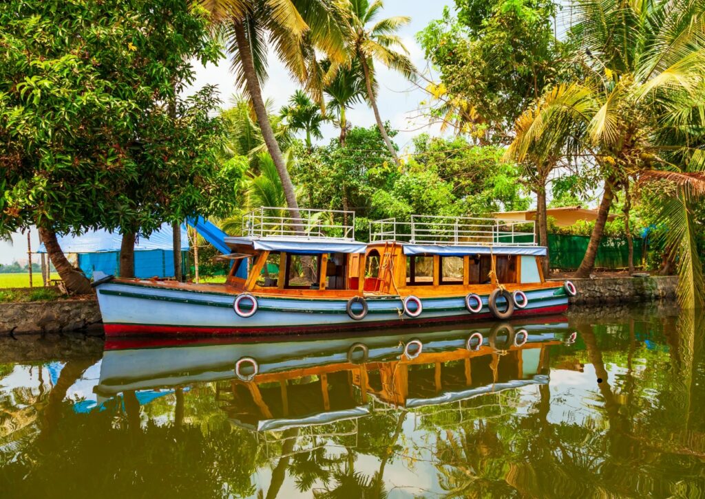 A boat floats on the Alleppey backwaters, surrounded by lush palm trees and tranquil water.