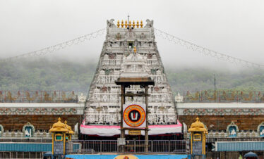 A large white structure, the Tirumala Tirupati Raja Gopuram, featuring elaborate carvings and architectural style.