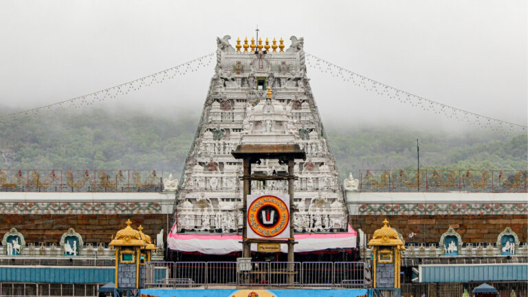 A large white structure, the Tirumala Tirupati Raja Gopuram, featuring elaborate carvings and architectural style.